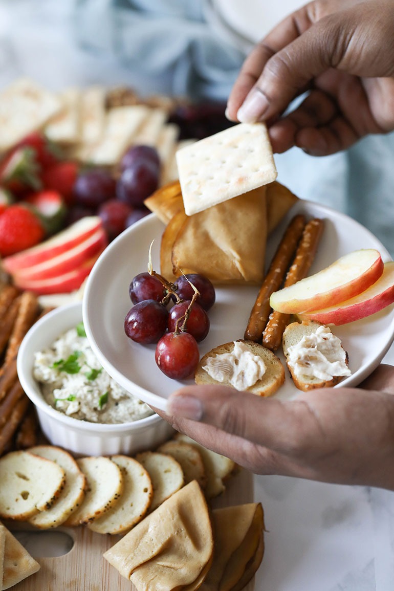 Easy Vegan Charcuterie Board with brown hand holding cracker
