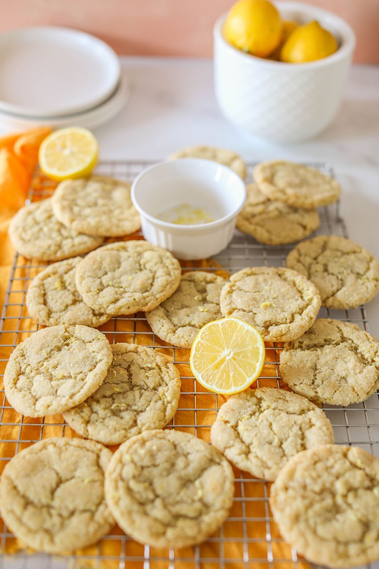 Vegan Lemon Sugar Cookies on a cooling rack with sliced lemons