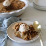 Vegan Apple Crisp on white plate with gold spoon