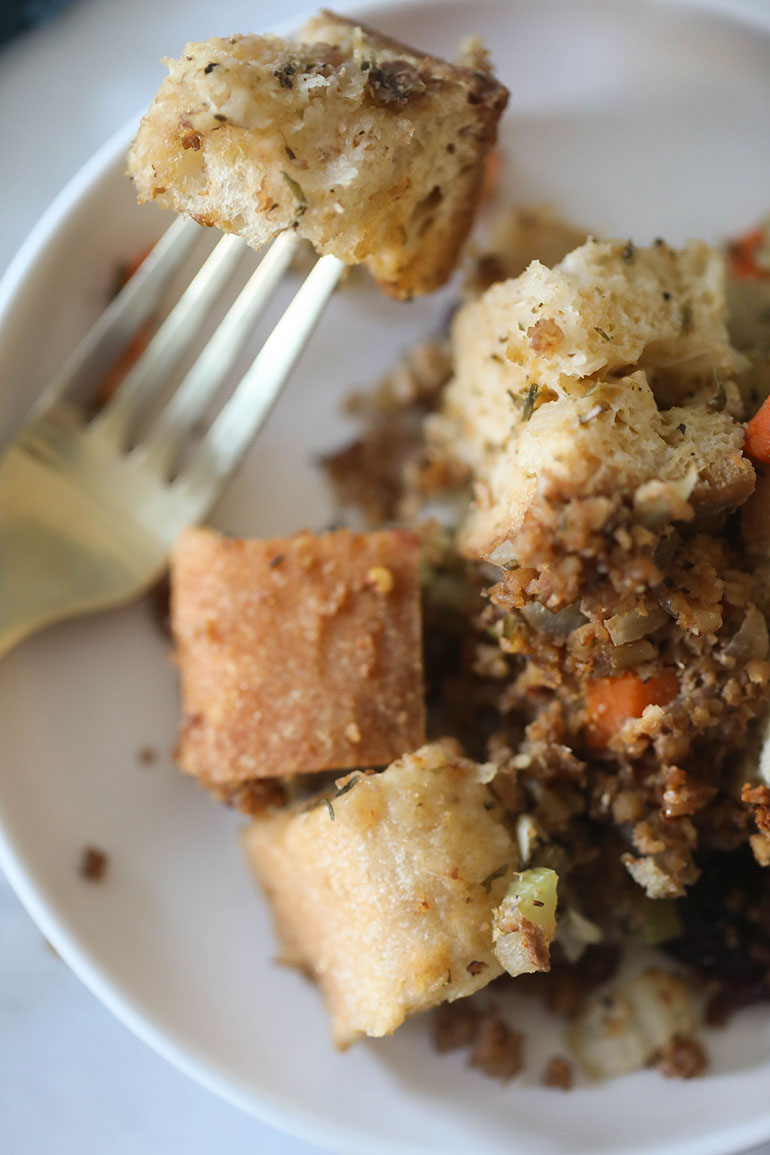 Vegan Sausage Stuffing on white plate with gold fork