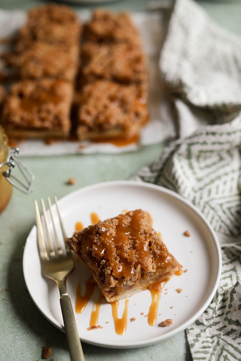 Vegan Caramel Apple Pie Bars on white plate with gold fork